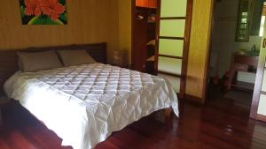 a bed with a white comforter in a room at Villa ManaOra in Taravao