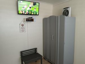 a room with a refrigerator and a tv on a wall at The Goose Nest in Struisbaai