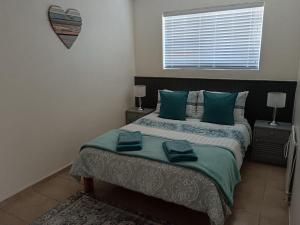 a bedroom with a bed with green pillows and a window at The Goose Nest in Struisbaai
