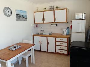 a kitchen with a table and a sink and a refrigerator at The Goose Nest in Struisbaai