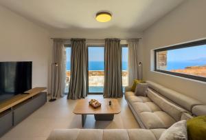 a living room with a couch and a tv at Villa Plora, by Estia in Áno Meriá