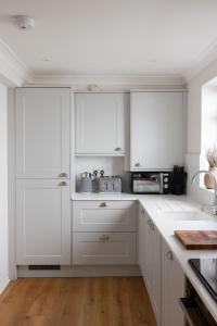 a white kitchen with white cabinets and a microwave at NEW - Herricks by The Butler Collection in Arundel