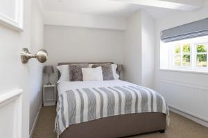 a white bedroom with a bed with a striped blanket at NEW - Herricks by The Butler Collection in Arundel