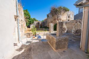 a stone courtyard with a stone wall and a table and chairs at HISTORIA - Dimore in Corte in Borgagne