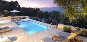 a swimming pool with chairs and a view at Paxos Sunrise Villas in Gaios