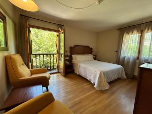 a bedroom with a bed and a chair and a balcony at Hotel Abetos in Torla-Ordesa