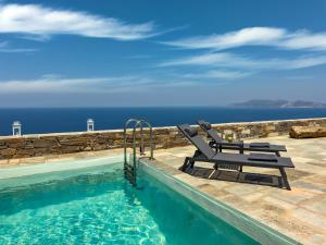 a swimming pool with two lounge chairs and the ocean at Villa Plora, by Estia in Áno Meriá