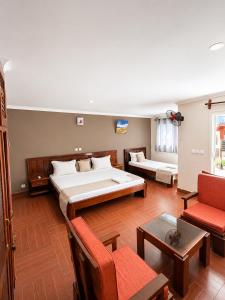 a large room with a bed and a couch and chairs at Hôtel Sofia Bellevue in Antsohihy