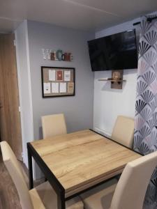 a dining room table with chairs and a flat screen tv at MH 556 - Océan Landes in Saint-Julien-en-Born