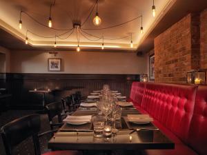 a long table in a restaurant with a red couch at Malmaison Hotel Leeds in Leeds