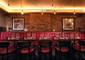 a dining room with a long table and red booths at Malmaison Hotel Leeds in Leeds