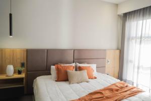a bedroom with a large bed with orange and white pillows at Amerian Chacras de Coria in Chacras de Coria