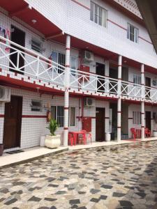 a building with red chairs and a courtyard at Pousada Maria Helena in Guaratuba
