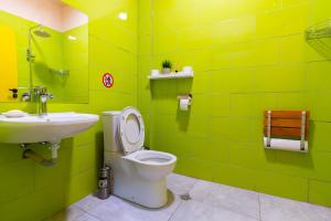 a green bathroom with a toilet and a sink at Green Cube Capsule Hostel in Sofia