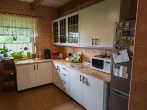 a small kitchen with white cabinets and a microwave at Pszczeli Ogród - dom na wyłączność z jacuzzi ze świeżą wodą in Dęba Koliszowy