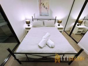 a bedroom with a bed with two white towels on it at Braddon Base in The Midnight, Heated Pool & Sauna in Braddon +8 photos