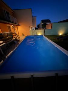 a large blue swimming pool in a backyard at night at Apartman Cherry in Višnjevac