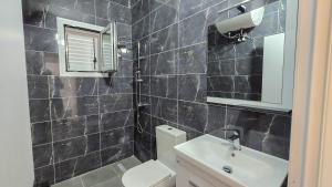 a black tiled bathroom with a toilet and a sink at Guesthouse - VILA QETESIA in Përmet