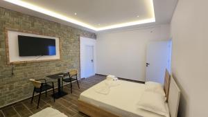 a bedroom with a bed and a tv on a brick wall at Guesthouse - VILA QETESIA in Përmet