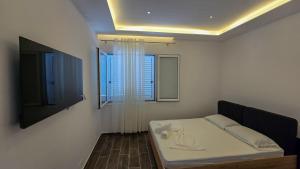 a bedroom with a bed with a window and a tv at Guesthouse - VILA QETESIA in Përmet +16 photos