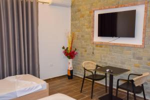 a living room with a table and a tv on a brick wall at Guesthouse - VILA QETESIA in Përmet