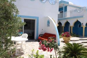 a patio with a red bench and a building at Dar Mimouna Djerba in Tianest