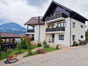 a white house with a black roof and some flowers at Aqualina Colibita - pe malul lacului in Colibiţa