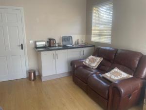 a living room with a brown leather couch and a kitchen at The perfect rest place in Omagh