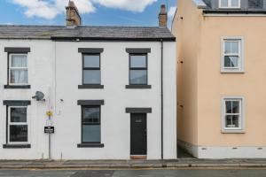 a white house with a black door on a street at Southend Cottage By Birch Stays in Penrith