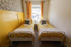 two beds in a small room with a window at Southend Cottage By Birch Stays in Penrith