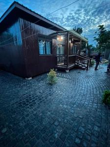 a small house with a brick patio next to a building at Embawwo Rustic Cabin in Entebbe