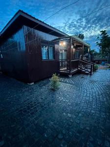 a small house with a brick patio in front of it at Embawwo Rustic Cabin in Entebbe