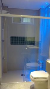 uma casa de banho com uma cabina de duche em vidro e um WC. em Apartamento Zapata Guarujá no Guarujá