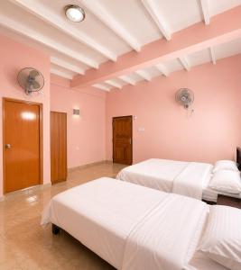 two beds in a room with pink walls at Prabha Garden Boutique Villa in Anuradhapura