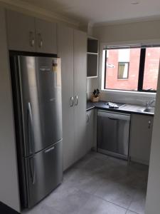 a kitchen with a stainless steel refrigerator and a window at Brooklyn Motor Lodge in Hamilton
