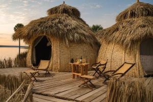 a wooden deck with chairs and a table and some huts at Fort Banya Resort in Eliye