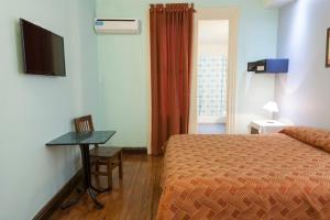 a hotel room with a bed and a table and a television at Hotel Reina in Buenos Aires