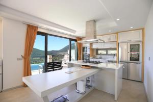 a kitchen with white counters and a large window at Villa Sydney in Kaş +33 photos