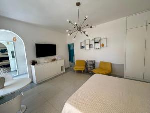 a living room with a television and yellow chairs at To Be Capri Sea view Rooms in Capri