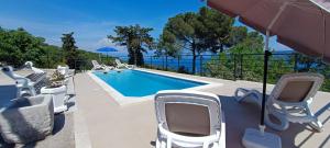 a swimming pool with chairs and an umbrella at Franelli in Zagore - Istrien in Brseč