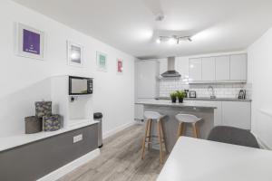 a kitchen with white cabinets and a counter with stools at Charming Two Bed - Two Bath Apt (25KM) in Headingley