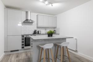 a kitchen with white cabinets and bar stools at Charming Two Bed - Two Bath Apt (25KM) in Headingley