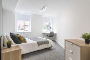 a bedroom with a bed and a desk and two windows at Charming Two Bed - Two Bath Apt (25KM) in Headingley +8 photos