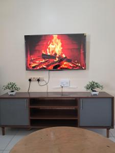 a tv sitting on a wall with a fireplace at Cozy 2 BR with 3 Beds, AC & Hot Shower at Buxton Point Apartments Off RG Road Gate A in Mombasa