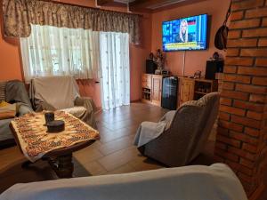 a living room with a table and a tv at Pszczeli Ogród - dom na wyłączność z jacuzzi ze świeżą wodą in Dęba Koliszowy