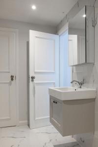 a white bathroom with a sink and a door at NEW - Herricks by The Butler Collection in Arundel +37 photos