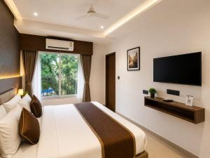 a bedroom with a large bed and a flat screen tv at The Kingsway Suites in Nagpur