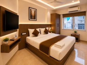 a bedroom with a large bed and a flat screen tv at The Kingsway Suites in Nagpur