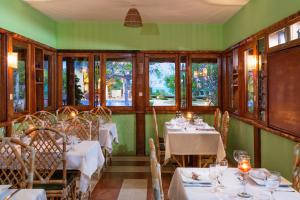 a restaurant with white tables and chairs and windows at Pousada Riacho dos Milagres in São Miguel dos Milagres