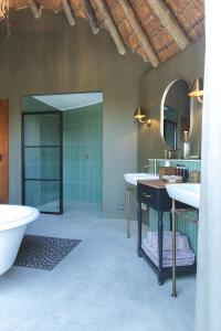 a bathroom with two sinks and a tub and a mirror at Last Word Makanyane in Laastepoort +24 photos
